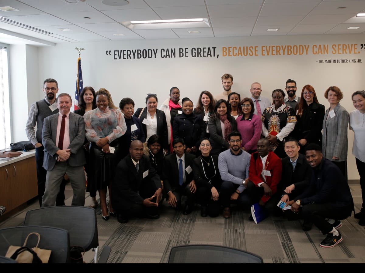 IVLP katılımcıları, Washington D.C.'deki AmeriCorps ofisinde "Everybody can be great, because everybody can serve" yazılı duvarın önünde toplu fotoğrafta